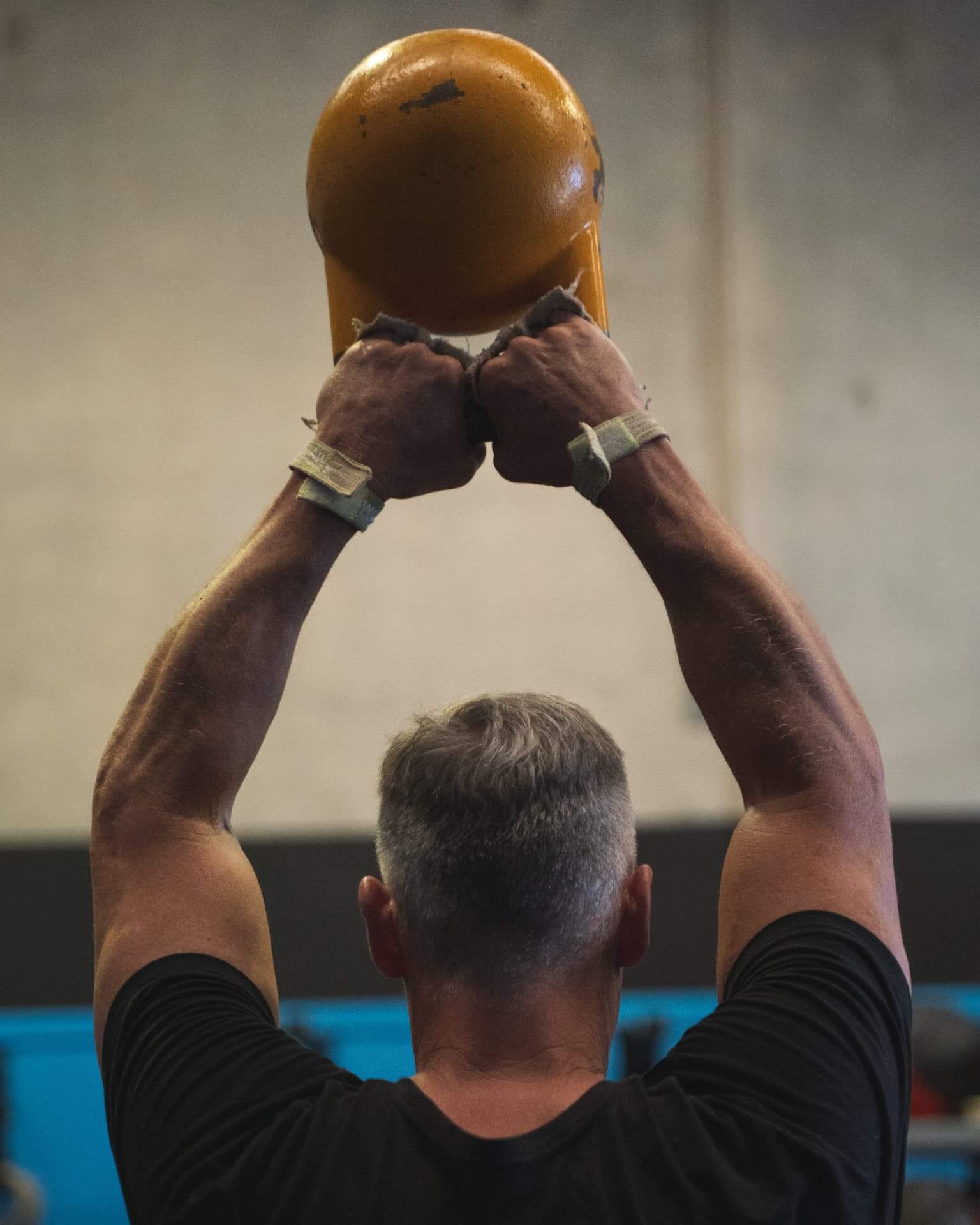 A long-time member pressing a kettlebell overhead at Niche CrossFit