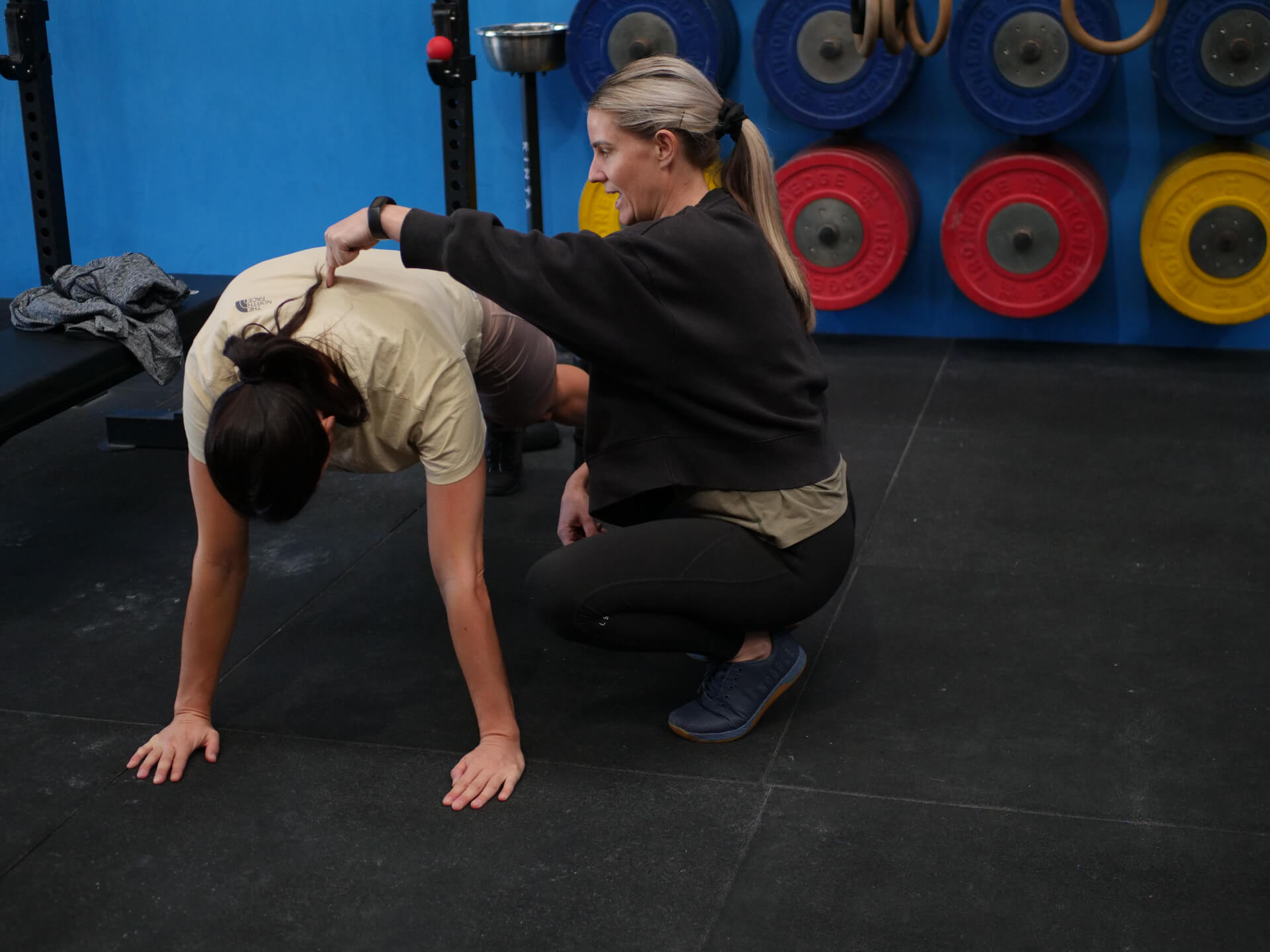 A coach giving hands-on positional cues to a member at Niche CrossFit