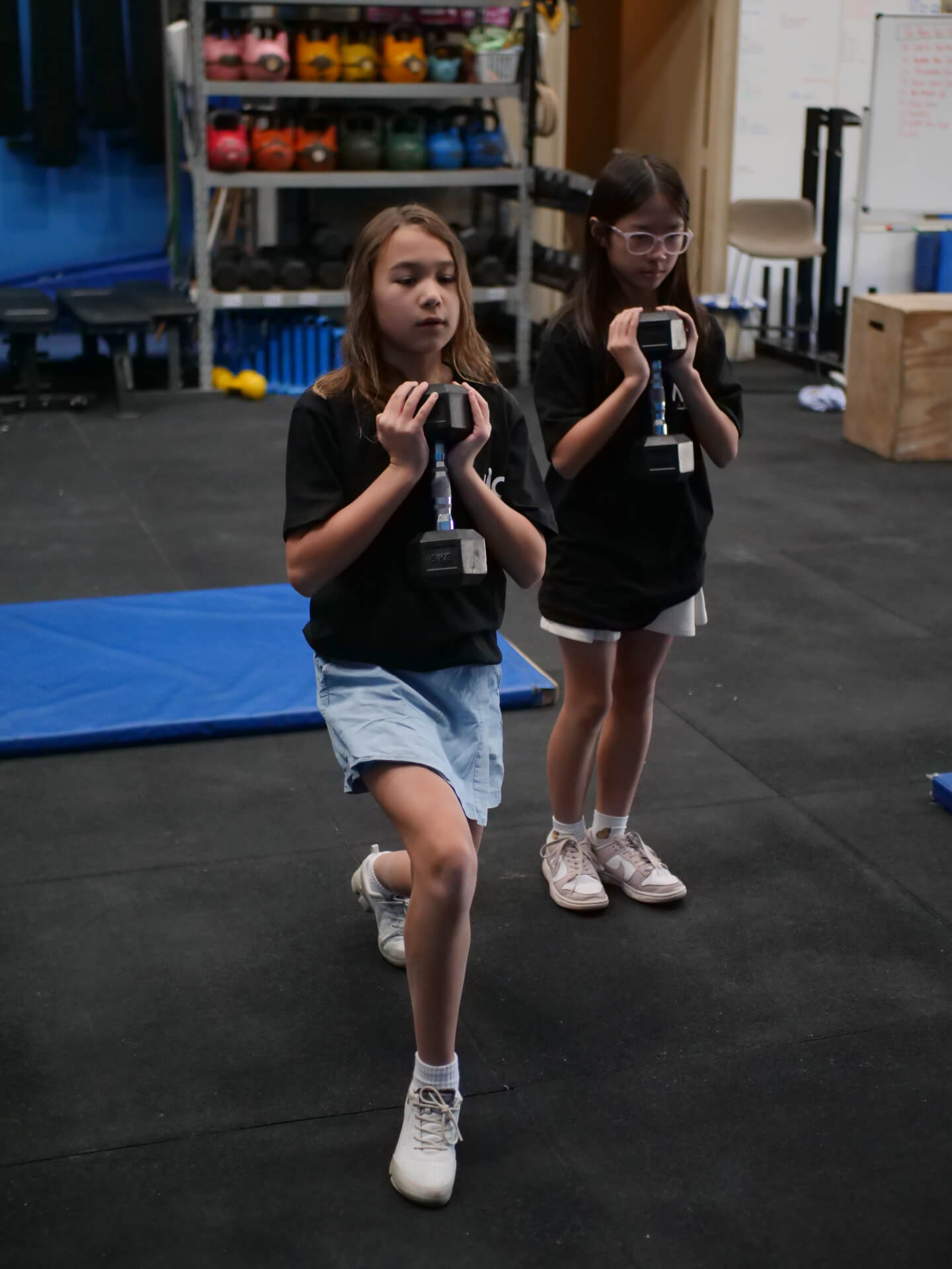 Young members performing dumbbell lunges